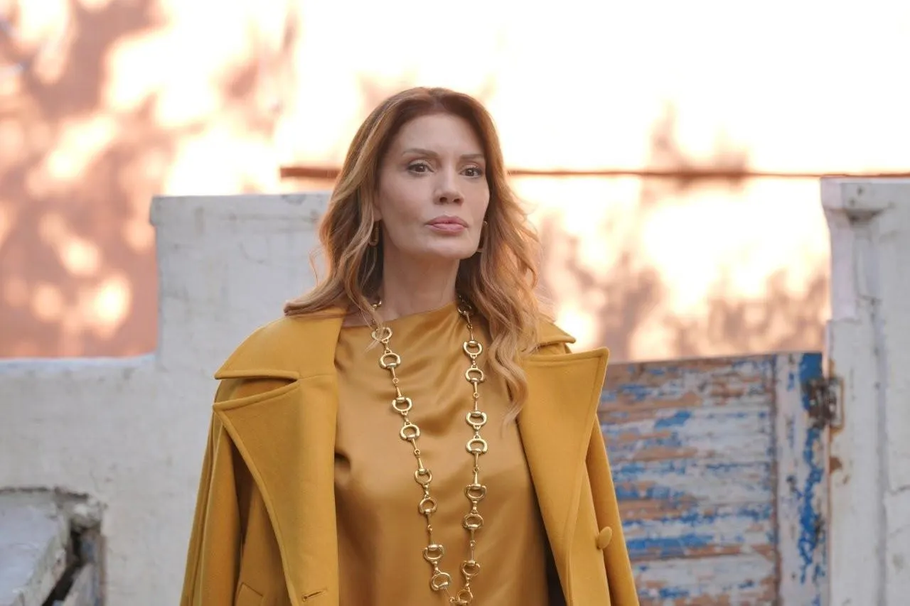 Hardal renkli kıyafet giyen bir kadın avluda duruyor.