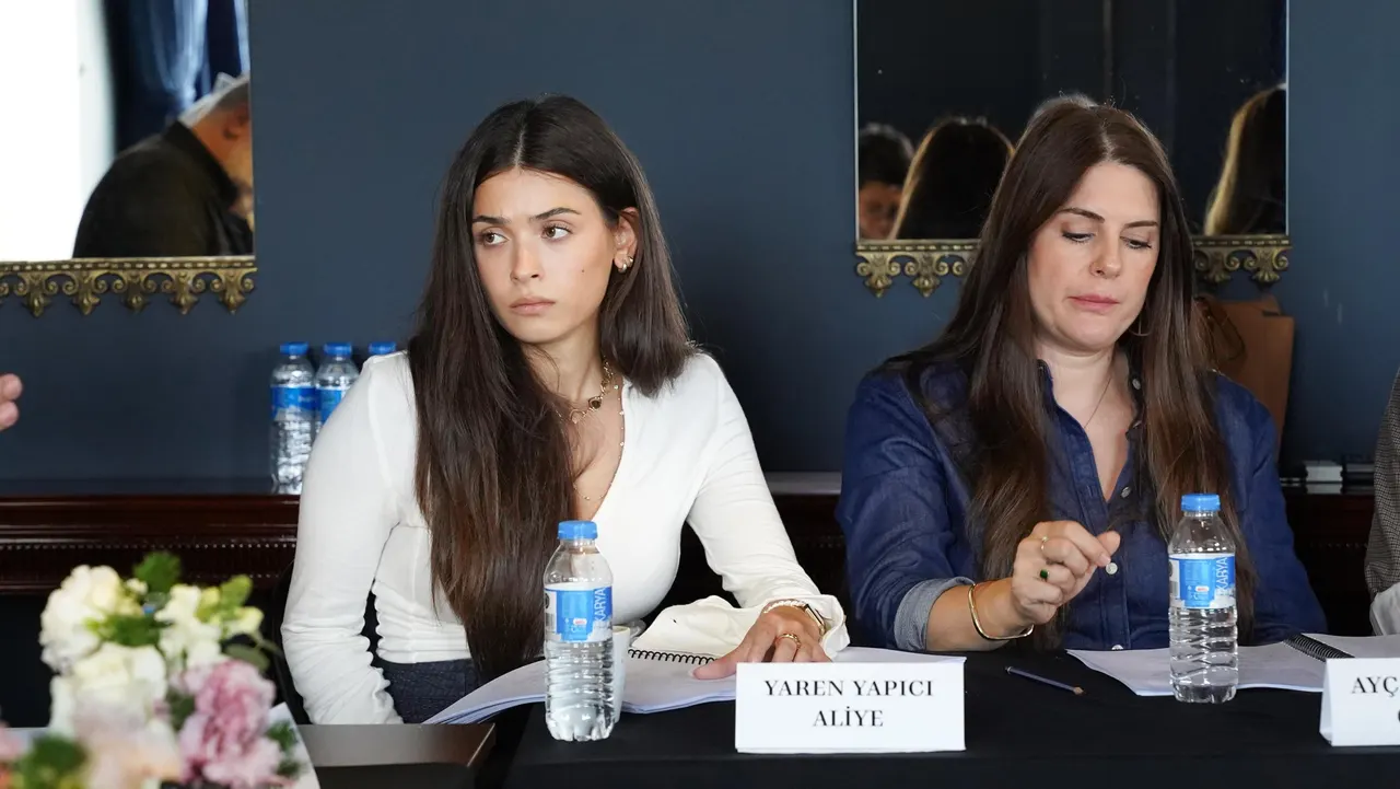 İki oyuncu okuma provası masasında yan yana oturuyor.