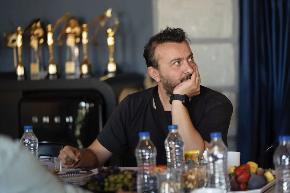 Ali Atay okuma provası masasında senaryo sayfalarının yanında oturuyor.