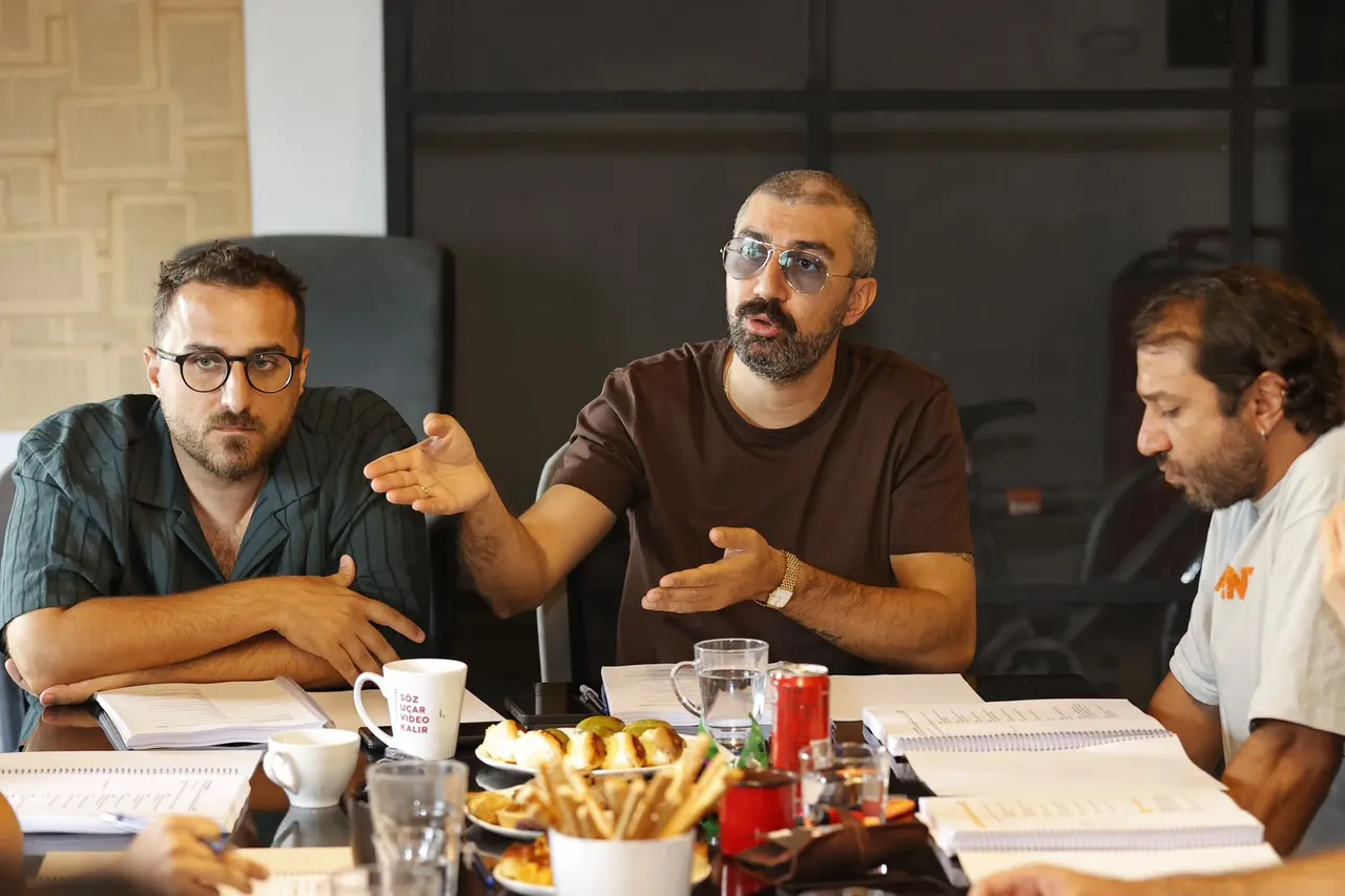 Nemlizade ekibinden üç kişi okuma provası masasında konuşuyor.