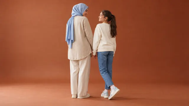 Veli eşliğinde çocuk ayakkabısı katalog çekiminde tabureye oturarak spor ayakkabılarını gösteren çocuk