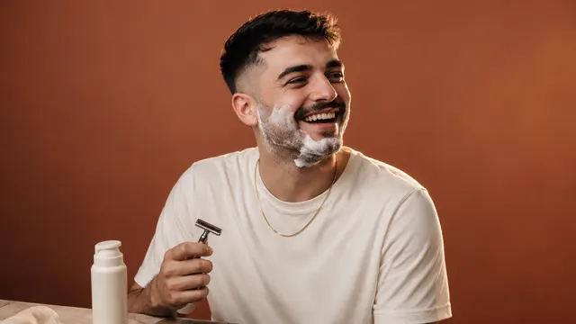 Ayna karşısında tıraş köpüğünü yüzüne uygulayan erkek oyuncunun reklam çekimindeki doğal bakım sahnesi
